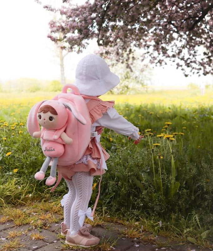 Dziecko z pluszową lalką Metoo z imieniem i plecakiem na plecach