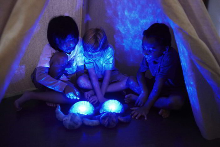 Dzieci z projektorem żółwiem wyświetlającym magiczny podwodny efekt świetlny z delikatnym ruchem fal